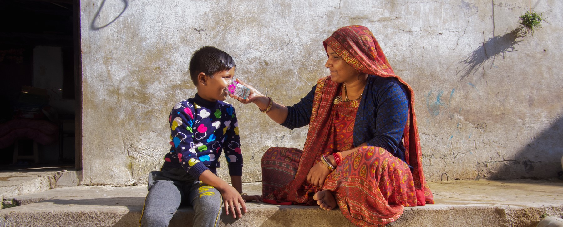 A woman from Jamgod village in Madhya Pradesh gives potable water to a young child to drink.