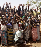 Members of the Water Users Association supported by USAID/TerresEauVie pose for a picture with their hands raised; women are well represented in the group.
