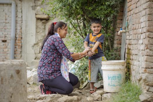 Environment and Public Health Organization (ENPHO) staff member, Radhika Ghamire, teaches four-year-old Rhythm Phuyal the technique for effective handwashing. In the aftermath of the 2015 Nepal earthquake, and now to prevent COVID-19 outbreaks, hand hygiene is critical to public health and community resilience.     Photo credit: Gavin Gough/CAWST