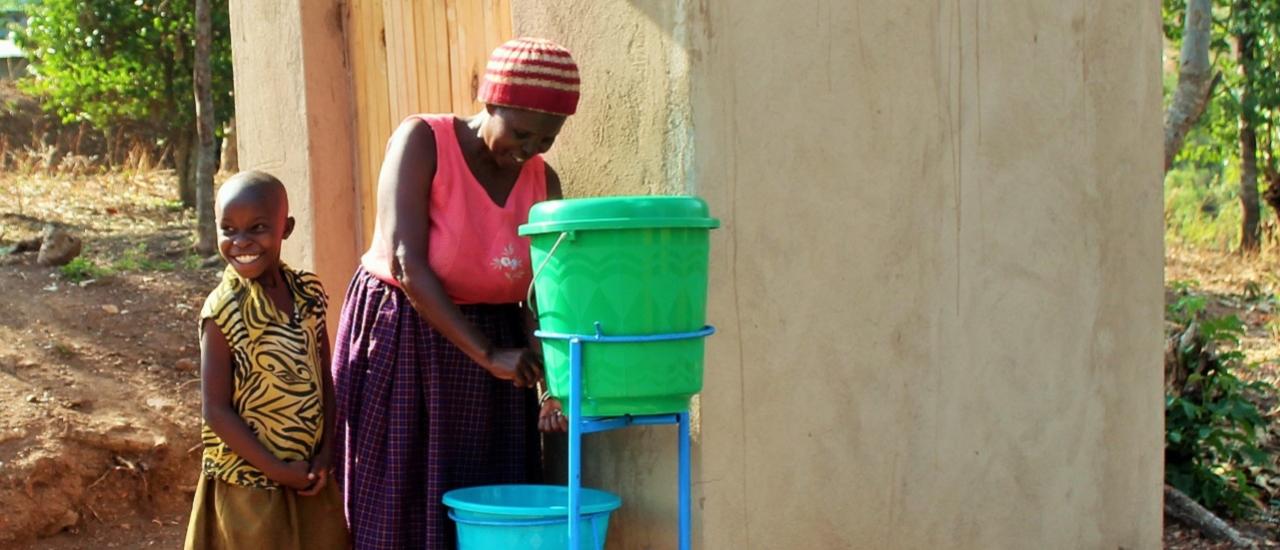 A mother washes her daughter’s hands outside her newly built latrine. Photo credit: Isuku Iwacu