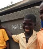 Students poses in front of their new school latrine build under the USAID WASH for Health program. Previously students could be forced to leave school or practice open-defecation if they needed to use that bathroom. Photo credit: Global Communities