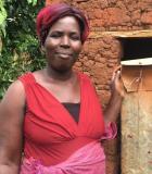 A participant in the Rural Household and Institutional Survey in Uganda stands with her improved latrine. Photo credit: FSG