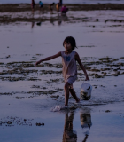 Girl with a bucket on the beach. Photo Credit: Water for Women Fund